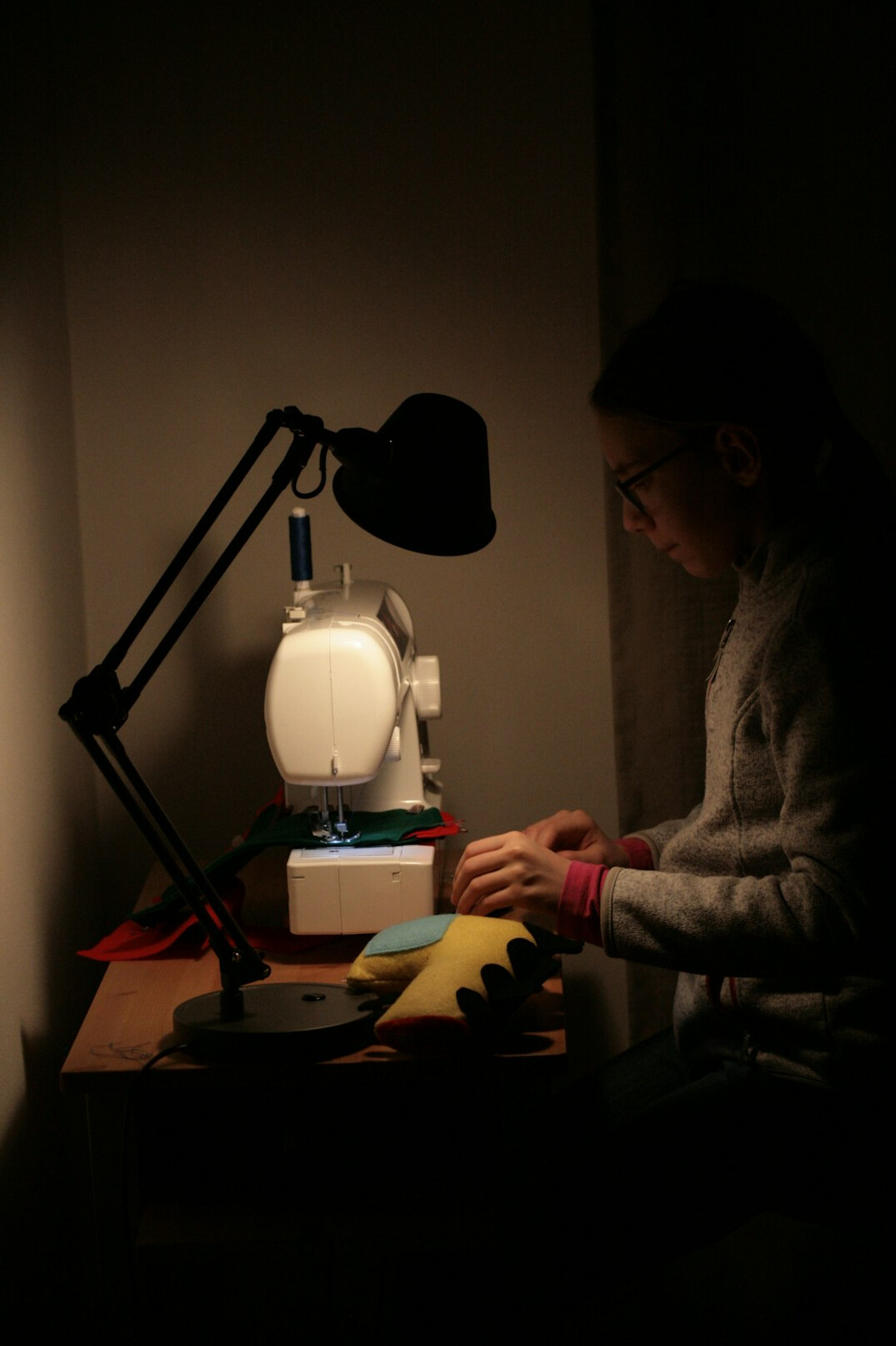Woman studying programming at a desk lit by a lamp at night